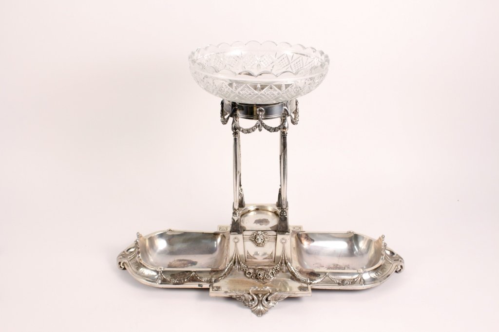 Victorian Silverplated Epergne w/ Cut Glass Bowl: Victorian silverplate epergne with scalloped edged cut glass bowl insert at center above floral swag decoration on four thin columns on a square plinth base with lion's head ornament above additional 