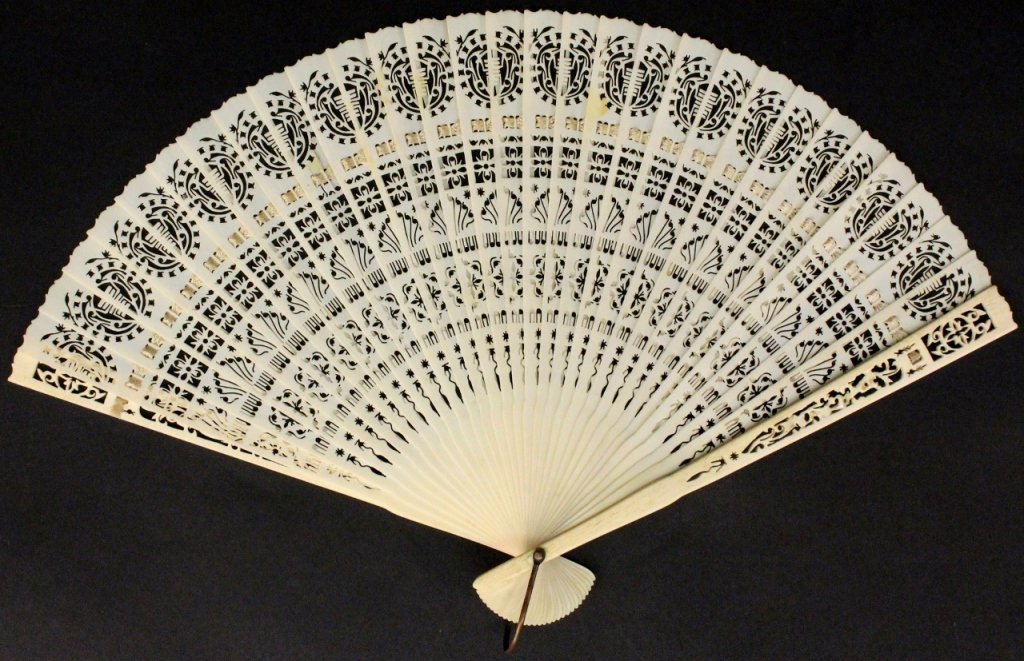 19th C. Pierced Ivory Ladies Fan: Continental School, 19th century. Ladies fan composed of thirty one finely pierced thin ivory sticks with heraldic shield motif at top above patera block, fern and floral pierced ornament. Unmarked. L