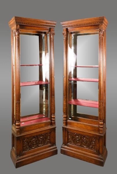 Pair of American 19th C. Display Cabinets: American, 19th century. Pair of matching Neoclassical style mahogany wood and glass display cabinets or vitrines with cornice top with dentilated edge above paneled blocks supported by scrolled capita
