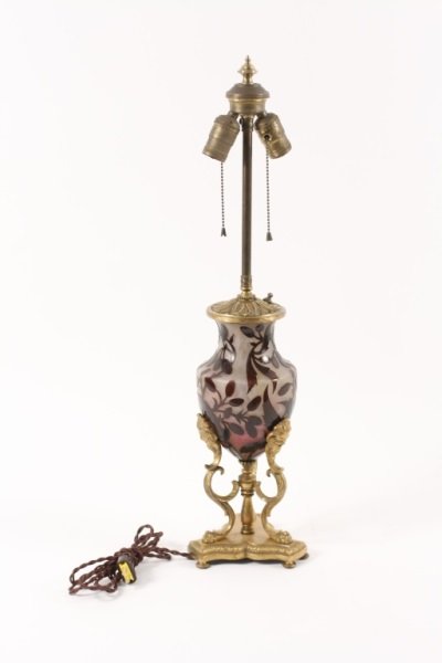 Daum Cameo Glass and Gilt Bronze Table Lamp: French, 20th Century. Daum cameo glass and gilt bronze table lamp of baluster form, the glass with berry laden leafy branches, raised on scrolling legs terminating in paw feet, further raised on a con