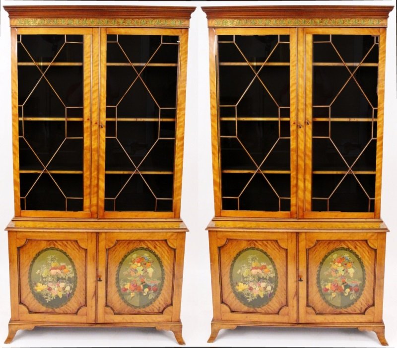 Pair of Edwardian Painted Satinwood Cabinets: English, Late 19th century (circa 1890). Pair of Edwardian matching satinwood cabinets with cornice above hand painted green plant motif frieze above two glazed hinged doors that open to three shelves