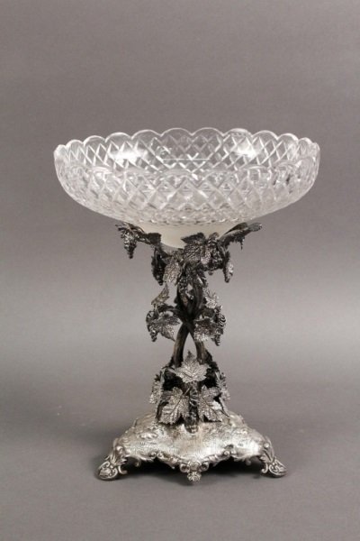 Silverplated Epergne w/ Cut Glass Bowl: Possibly English, Early 20th Century. Silverplate single bowl epergne surmounted with a cut glass bowl with scalloped edge and cross-hatched motif with conical base, the post cast in the form of inter
