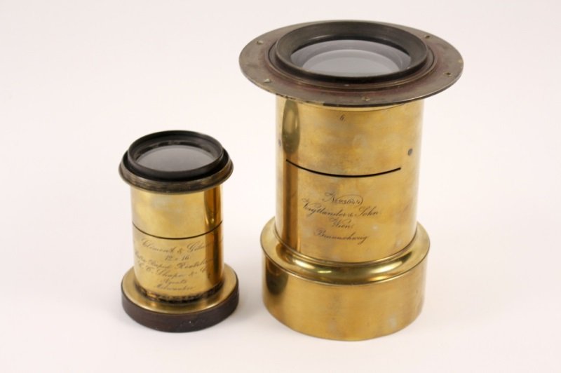 Two 19th C. Brass Lenses, One Voigtlander: American & Austrian, 19th century. Collection of two engraved brass lenses comprising of a taller Voigtlander & Sohn, Wien, Braunschweig No. 23644 lens (approximate height 8.8", diameter 6.75"); and a