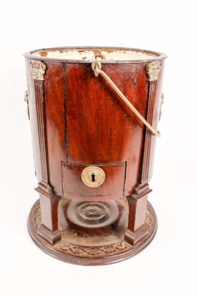 19th Century French Gilt Bronze Mounted Cellarette: French, 19th Century. Mahogany and gilt metal mounted cellarette or wine cooler, of round form, with carrying handle and removable copper liner, the exterior mounted two ram masks and four gilt capped