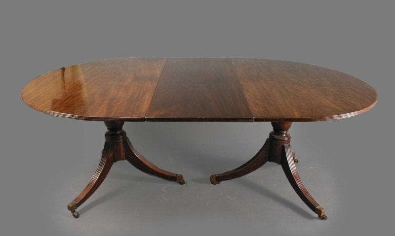 George III Style Triple Pedestal Dining Table: English, 20th Century. George III style mahogany triple pedestal extending dining table with two additional leaves, the top with rounded corners and reeded edge, raised on three baluster form standard