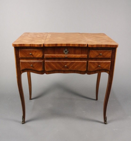 French Walnut Poudreuse or Dressing Table: French, Early 20th Century. French walnut poudreuse or dressing table walnut with top trisected, the central section lifting to an mirror, the sides hinged and opening outward, over a pull-out gilt to