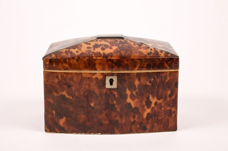 Regency Tortoiseshell Tea Caddy: English, 19th century. Regency casket form tea caddy with tortoiseshell veneer on exterior with metal monogram plate at top of hinged lid that opens to reveal two storage compartments within with ivor