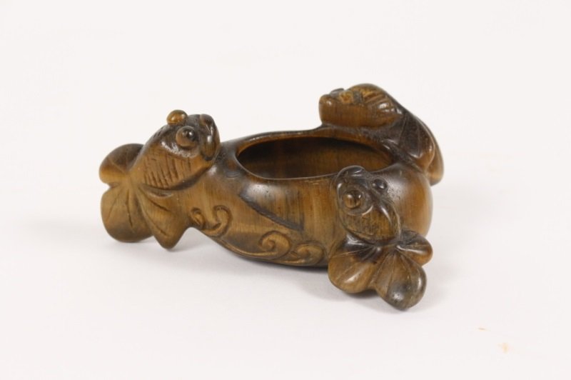 Tiger Eye Carved Inkwell with Koi Fish & Waves: A carved tiger eye inkwell with three carved coy fish surrounding and incised wave forms on the exterior. Approximately 1.5" tall x 3.5" wide x 2.25" deep.