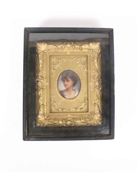 Framed Oval Hand Painted Figural Porcelain Plaque: Continental School, Late 19th/Early 20th century. Oval porcelain plaque hand painted with young woman with curly dark brown hair pulled up wearing gold necklace contained within an ornate gilt frame f