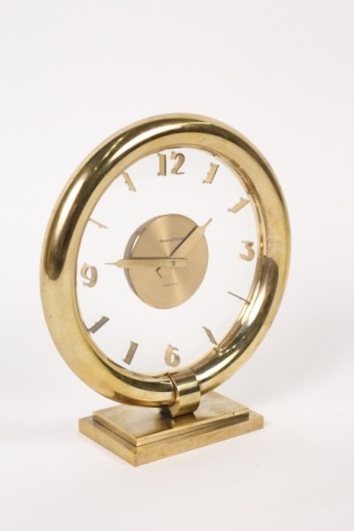 Jaeger-LeCoultre Art Deco Gilt Brass Mantel Clock: Jaeger-LeCoultre (Swiss, 1833- ). An art deco gilt brass mantel or desk clock, model no. 3547, with round glass face surrounded by tubular brass structure and mounted on a brass plinth, with Arabic nu