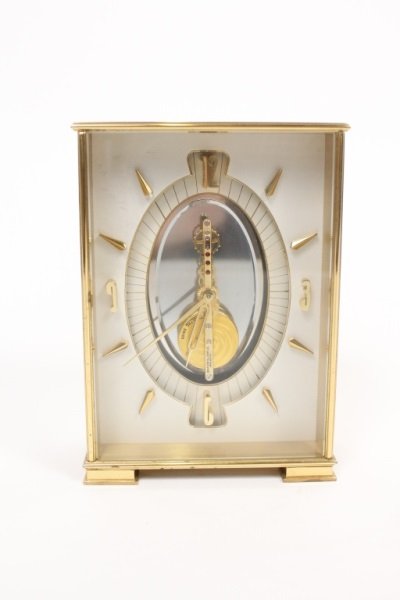 Jaeger-LeCoultre Art Deco Gilt Brass Desk Clock: Jaeger-LeCoultre (Swiss, 1833- ). A 20th century gilt brass mantel or desk clock in the Art Deco style decorated with three gemstones, possibly rubies, on the central structure, with face comprising o