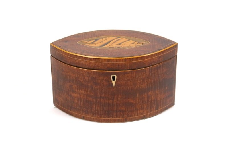 Almond Form Mahogany Tea Caddy w/ Shell Motif: English, 19th century. A mahogany almond form tea caddy with inlaid shell motif on lid within an almond shaped cartouche decorated with ebony line borders. Hinged lid opens to reveal two interior lidd