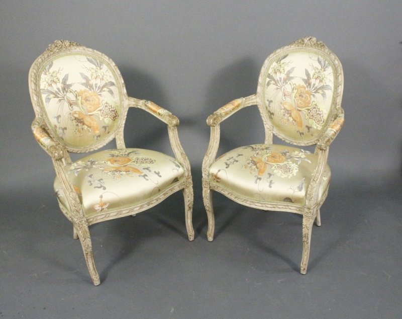 Pair of Louis XV Style Cream Painted Fauteuils: French, 19th century. Pair of matching Louis XV style armchairs or fauteuils with cream painted frames with antiqued or weathered finish. Oval backs with ribboned border and floral crest at top, acant