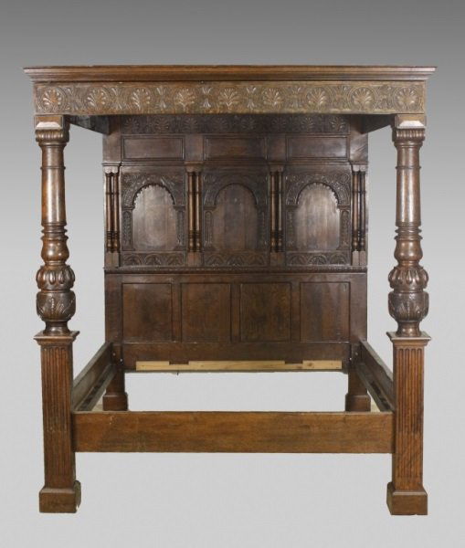 English Oak Carved Tester Bed: English reproduction of a 17th C oak tester bed with turned Ionic capitals and foliate and gadroon cup and cover posts supporting a 12 panel tester with Anthemion carved cornice over a head-board with