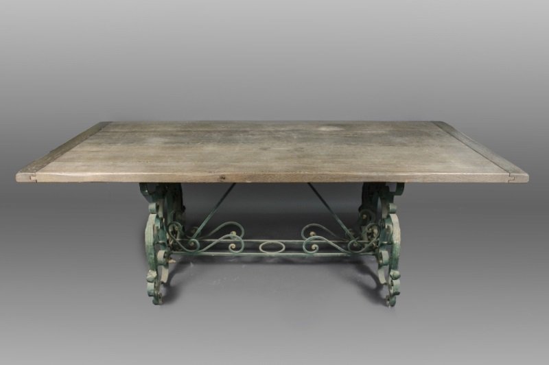 Scrolled Iron Trestle Table w/ Distressed Oak Top: An iron and oak table dining table with distressed thick grayed oak wood top set upon scrolled green painted iron trestle supports united by double scrolled stretchers with diagonal supports to top, d