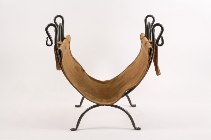 Contemporary Iron & Leather Log Holder: Contemporary iron and tan leather folding log holder with brushed exterior with textured accents at ends of serpentine accents. Holder open and extended approximate height 20.4", width 21.25", depth 1