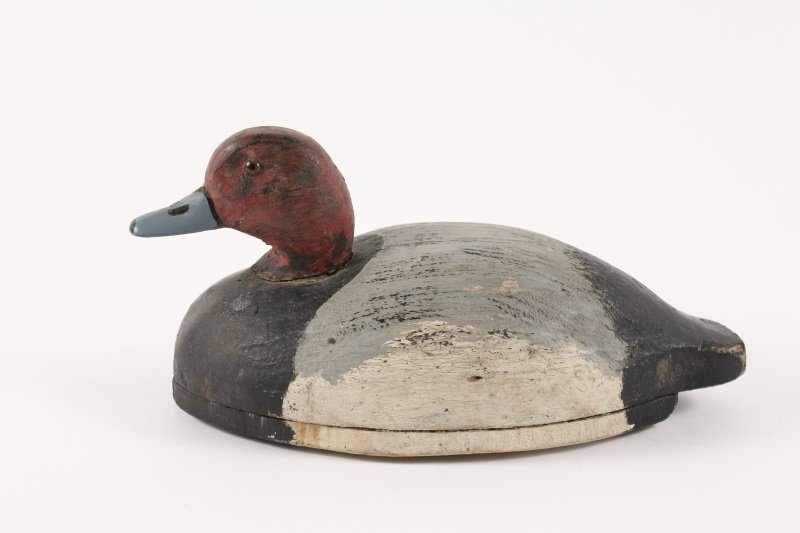 L.L. Bean Polychrome Duck Decoy, Circa 1908: L.L. Bean (American, Early 20th century), carved and polychromed wood duck decoy with red head with yellow glass eyes and blue bill above black, grey and white body. Underside carved with LLBEAN and 1