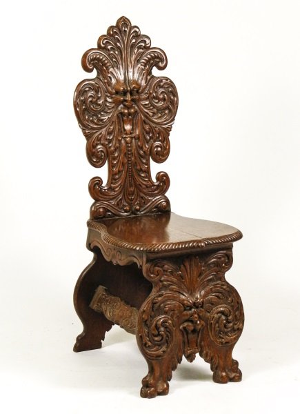Renaissance Style Oak Hall Chair, Sgabello Form: American Renaissance style oak hall chair in Sgabello form with the back elaborately carved with scrolling foliage and centered with grotesque or North Wind mask, the shaped seat with gadrooning over 