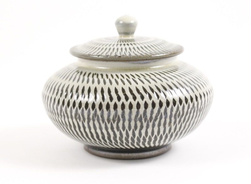 Japanese Black & White Chatter Lidded Jar, c.1840s: Japanese, circa 1840s, Edo Period (1603-1868). A lidded gray pottery jar of typical form with iron oxide black high gloss base glaze overlaid with white slip having chatter patterning allowing the bla