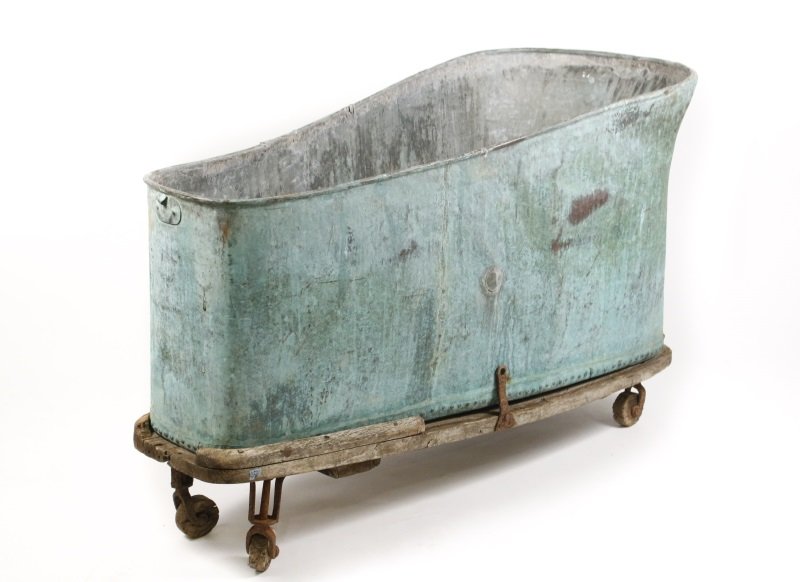Large Copper Bathtub on Wooden Stand w/ Wheels: 19th century copper bathtub, probably French, with aged verdigris finish, slightly rolled edge, elongated form with tapering body and height. Original spigot to one end. The base with rivets mounted o