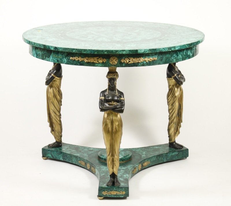 Empire Style Malachite Veneered Center Table: Continental, 20th century. Empire style malachite, patinated and gilt bronze center table with circular top over a ormolu mounted apron on 3 bronze Egyptian style figural supports united by a concave 