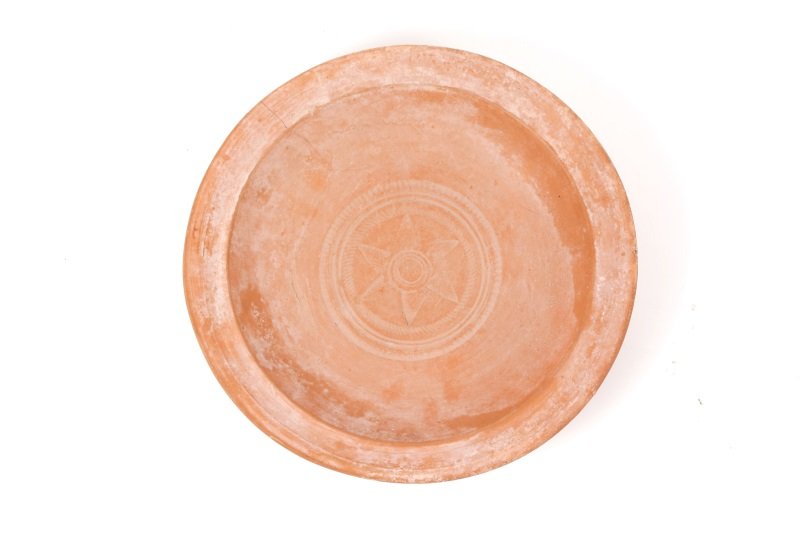 Large Roman Red Ware Round Plate w/ Star Motif: North Africa, c. 3rd/ 4th century AD. A thrown red slip round plate or shallow bowl with impressed circular bands to center surrounding a six point star form medallion. Approximately 10.5" diameter.