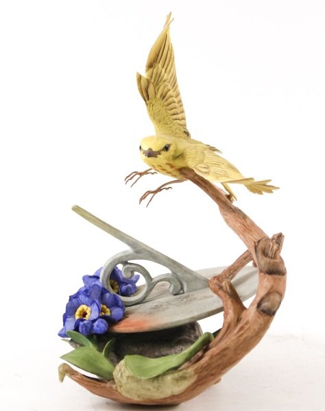 Boehm Yellow Warbler Above Sundial Figurine: Edward Marshall Boehm limited edition "Yellow Warbler" (40137) porcelain figurine depicting a flying yellow warbler bird above a wooden branch and purple to blue flowers on top of a circular sundial.