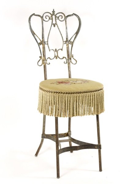 Victorian Vanity Chair w/ Floral Needlepoint Seat: American, late 19th/ early 20th century. A Victorian vanity chair with scrolled back, the structure of chair from cast gilt iron and the scrolled back of cast gilt white metal or spelter, the trapezoi