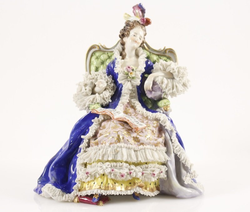 Large Volkstedt Porcelain, Woman in Chair w/ Lace: Volkstedt Porcelain (German, 1760- ). A large porcelain sculpture depicting a beautiful young lady seated in a green tufted upholstered wooden chair wearing ornate dress of gilt pink lace over yellow 