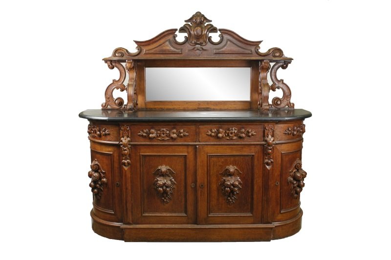 American Rococo Revival Mirrored Back Sideboard: American, circa 1850. Rococo Revival oak carved mirrored back sideboard, attributed to Alexander Roux (1813 to 1886), New York, the superstructure centered with cabochon over a shaped shelf supported