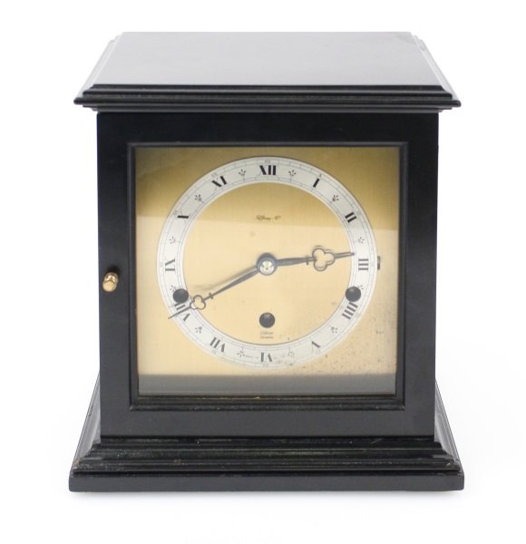 Black Cased Mantel Clock, F.W. Elliott Movement: English, 20th century. Westminster chime mantel clock of simplified form with cornice form top above square glass paneled case with black lacquered finish. Hinged glazed door at front opens to brass f