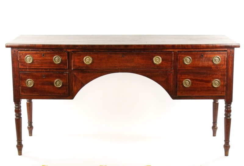 English Regency Mahogany Sideboard: English, early 19th century. English Regency mahogany with ebony stringing sideboard, the rectangular single board top above a frieze drawer flanked by a deep cellar drawer to one side and a pair of d