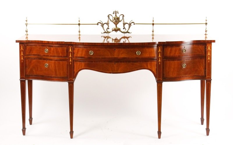 Karges Inlaid Mahogany Hepplewhite Style Sideboard: American, 20th century. Karges inlaid mahogany Hepplewhite style sideboard with brass-rail gallery to the back over a serpentine fronted top and conforming case decorated with satinwood stringing and 