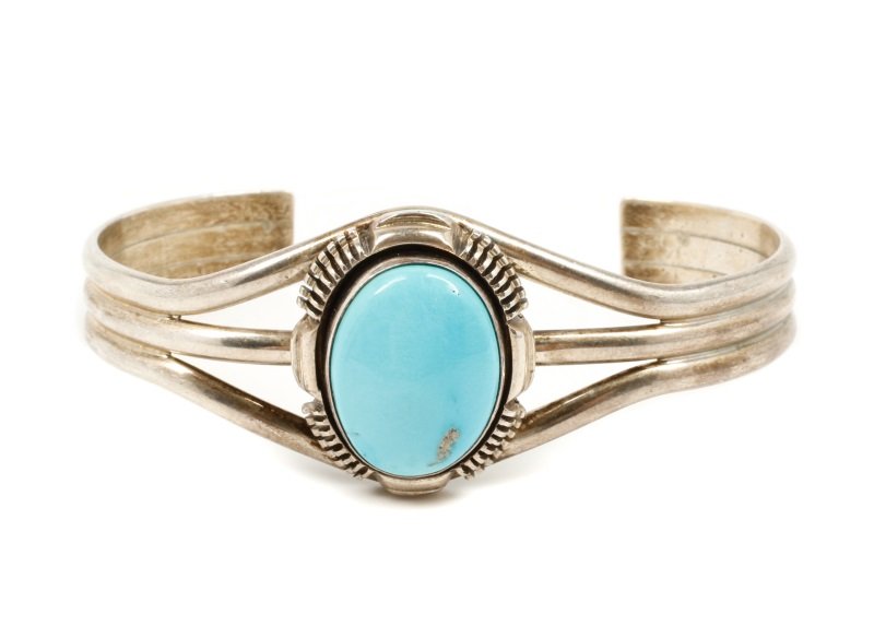 Leo Yazzie Navajo Sterling & Turquoise Bracelet: Leo Yazzie (Navajo, 20th century to contemporary). Sterling silver and turquoise bracelet with oval cabochon turquoise at center within tribal bezel joined by three thin bands. Marked on back with "St