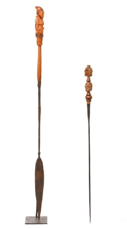 Collection of 2 African Carved Wood Spears: African, 20th century. Group of two hand carved wood figural ceremonial spears comprising of one depicting a nude female mother with arms at sides with young child on back on handle above thin metal s