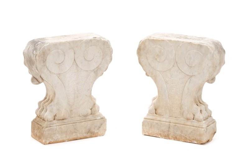 Pair Of Carved Marble Lion's Paw Pedestals: Italian, 20th century. Pair of carved marble pedestals or low table legs, or bench legs, each with mirrored lion's paw and flared leaf (possibly acanthus)motif to sides, with scrolled elements, with t
