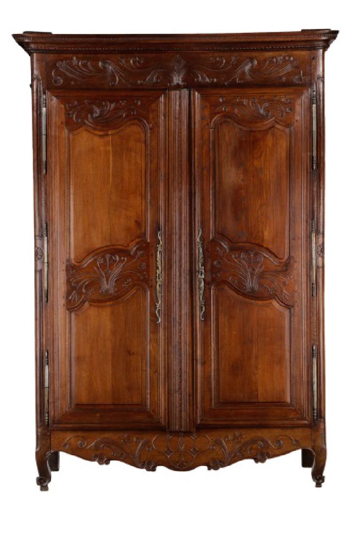 French Provincial Carved & Stained Oak Armoire: French, late 18th/early 19th century. A Provincial carved and stained oak armoire, having an overhanging molded top, above a cornice with bas relief carved scrolled foliates and vines, with two overla