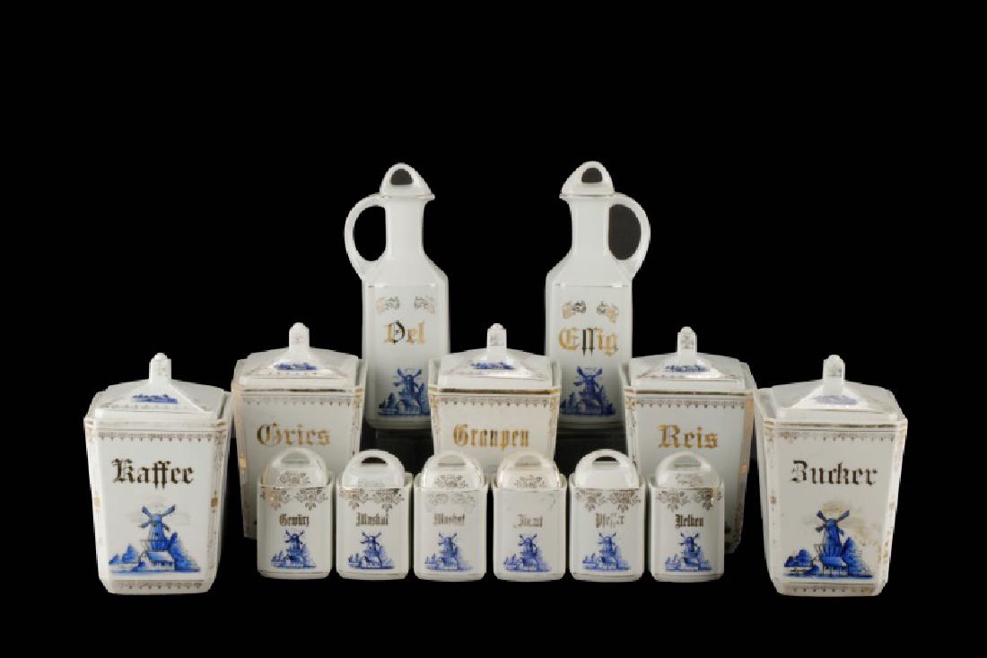 Set, 13 German Blue Delft Style Kitchen Canisters: German, mid 20th century. A set of thirteen Blue Delft type porcelain lidded condiment canisters, each decorated with a blue windmill and gilt decoration with a gilt name in German, including five lar