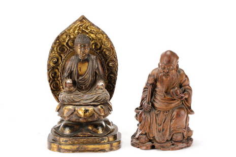 Two Chinese Carved Wood Buddhistic Figures: Chinese, 20th century. A group of two carved wood Buddhist figures comprising one gilded and polychrome lacquered seated Buddha on a lotus throne, and one carved bamboo figure of Shou seated and holdi