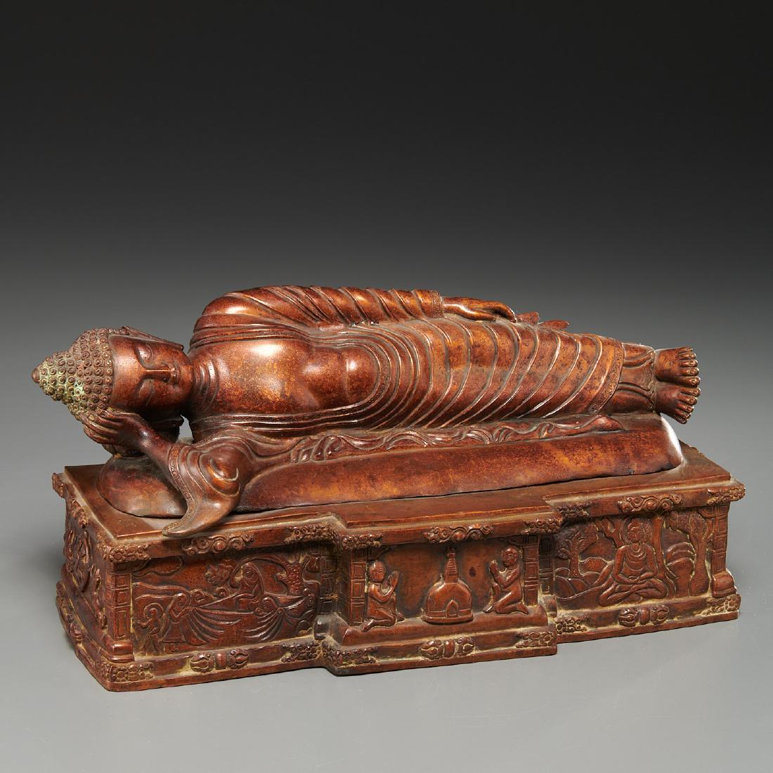 Antique copper alloy Parinirvana Buddha: Antique copper alloy Parinirvana Buddha, Likely 19th c., Sino-Tibet, cast in two parts, the reclining Shakyamuni Buddha in robes on a base relief cast with scenes of devotion, 9"h, 14.5"l x 5"w Proven