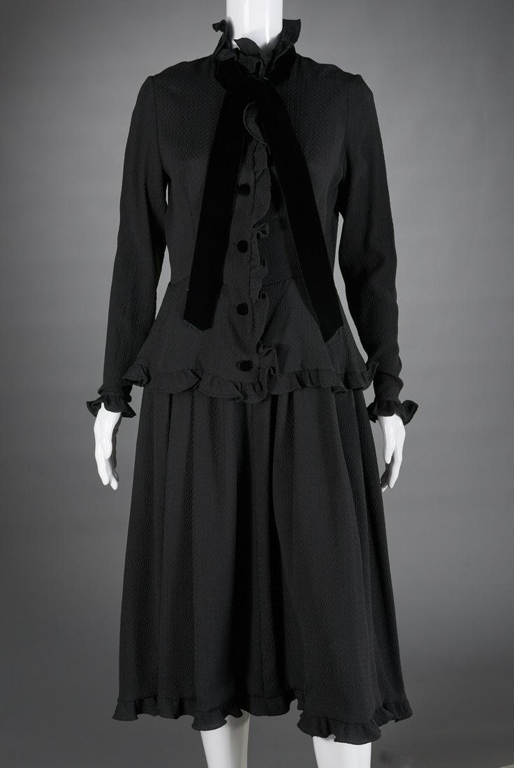Vintage Valentino Boutique black dress: Vintage Valentino Boutique black dress, c. 1970's, belted silk dress with button front and peplum waist detail, button sleeves, ruffle and velvet trim, high neckline with tie, size 12, 36"b, 15.5"sh, 