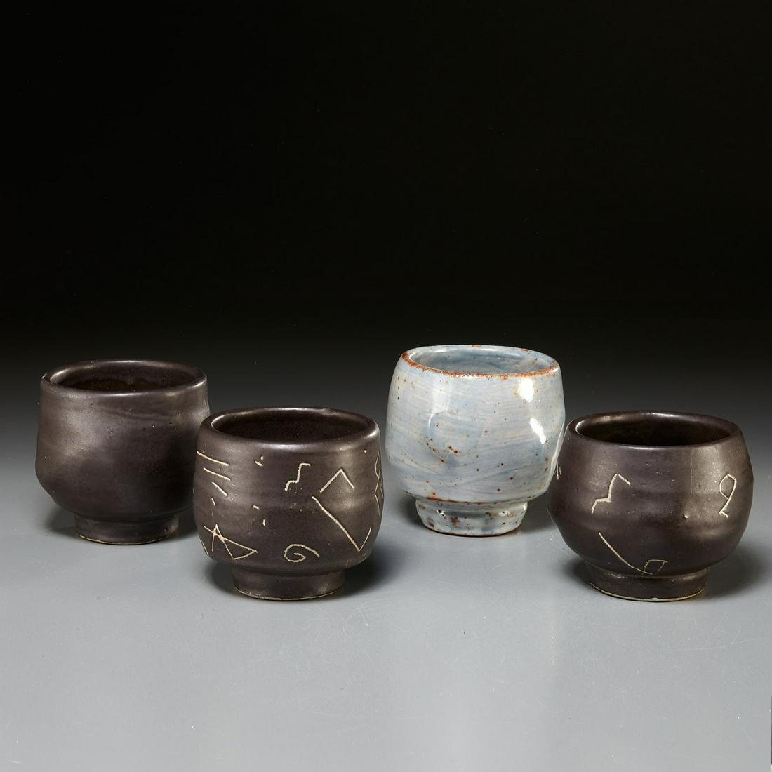 (4) Chris Gustin footed ceramic whiskey cups: (4) Chris Gustin footed ceramic whiskey cups, 20th c., incl. (1) chocolate brown glaze cup, (1) gray glaze cup, and (2) chocolate brown glazed cups with hieroglyphic inspired decoration, no visible ma
