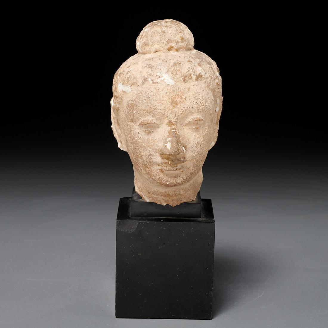 Gandharan stucco Buddha head: Gandharan stucco Buddha head, Likely ancient (c. 2nd c. AD), Pakistan region, finely carved features with hair in topknot, mounted on slate stand, 6"h x 5"l x 4"w (bust), 9"h (total)