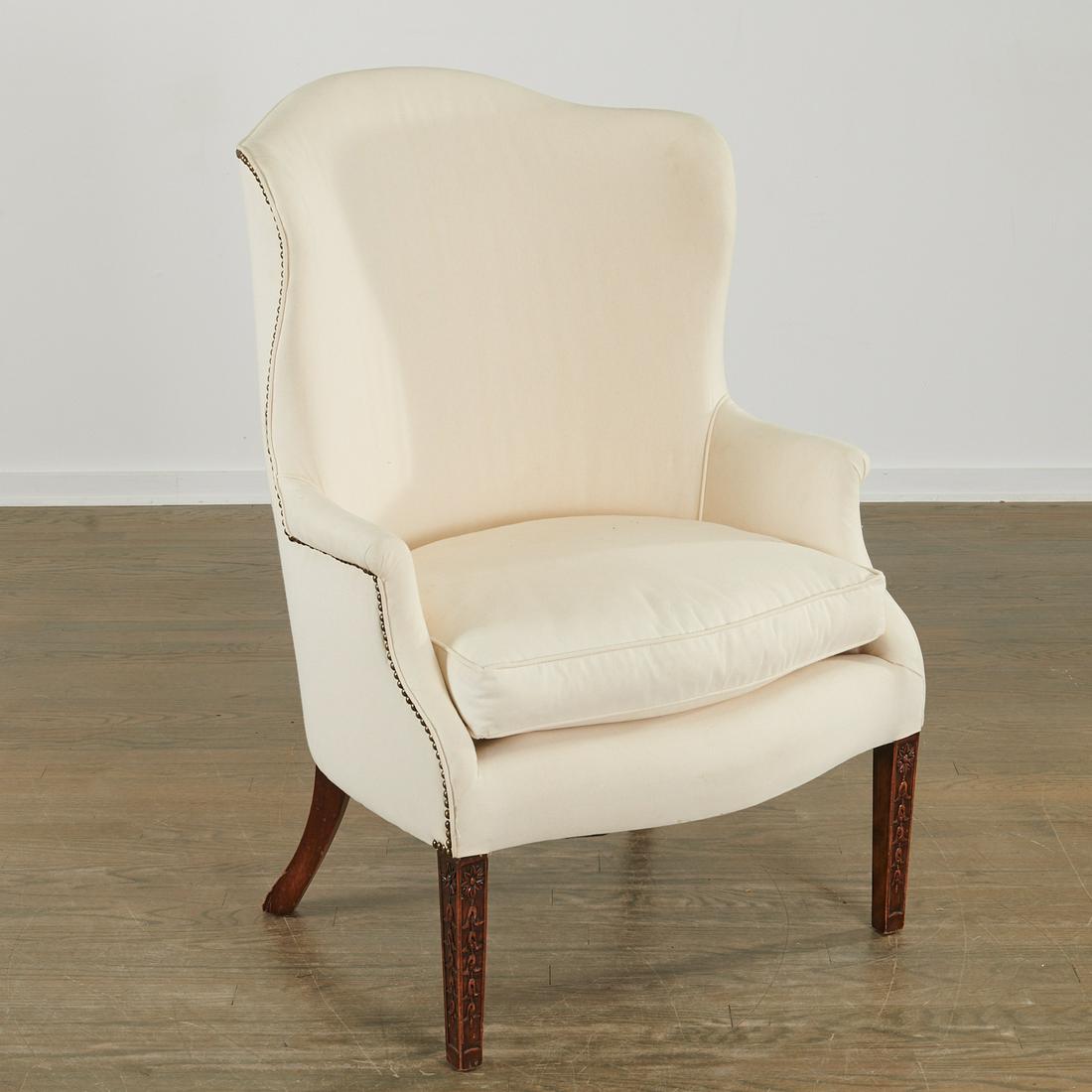 Hepplewhite style carved mahogany wing chair: Hepplewhite style carved mahogany wing chair, First quarter 20th c., England, white linen upholstery, brass rivets, the black and red painted square tapering legs incised with bellflowers, 42.5"h x 29