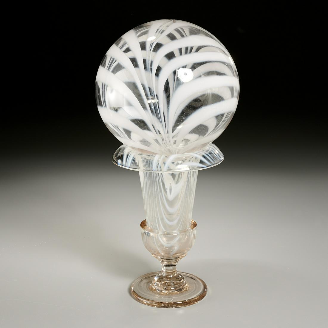 Victorian Marbrie Glass Witch Ball on Vase Stand: Victorian Marbrie Glass Witch Ball on Vase Stand, Late 19th c., colorless glass with cream loops, vase: 8 1/2" h, ball: 7 1/2" dia Provenance: The Collection of Elizabeth "Betty" Seeler