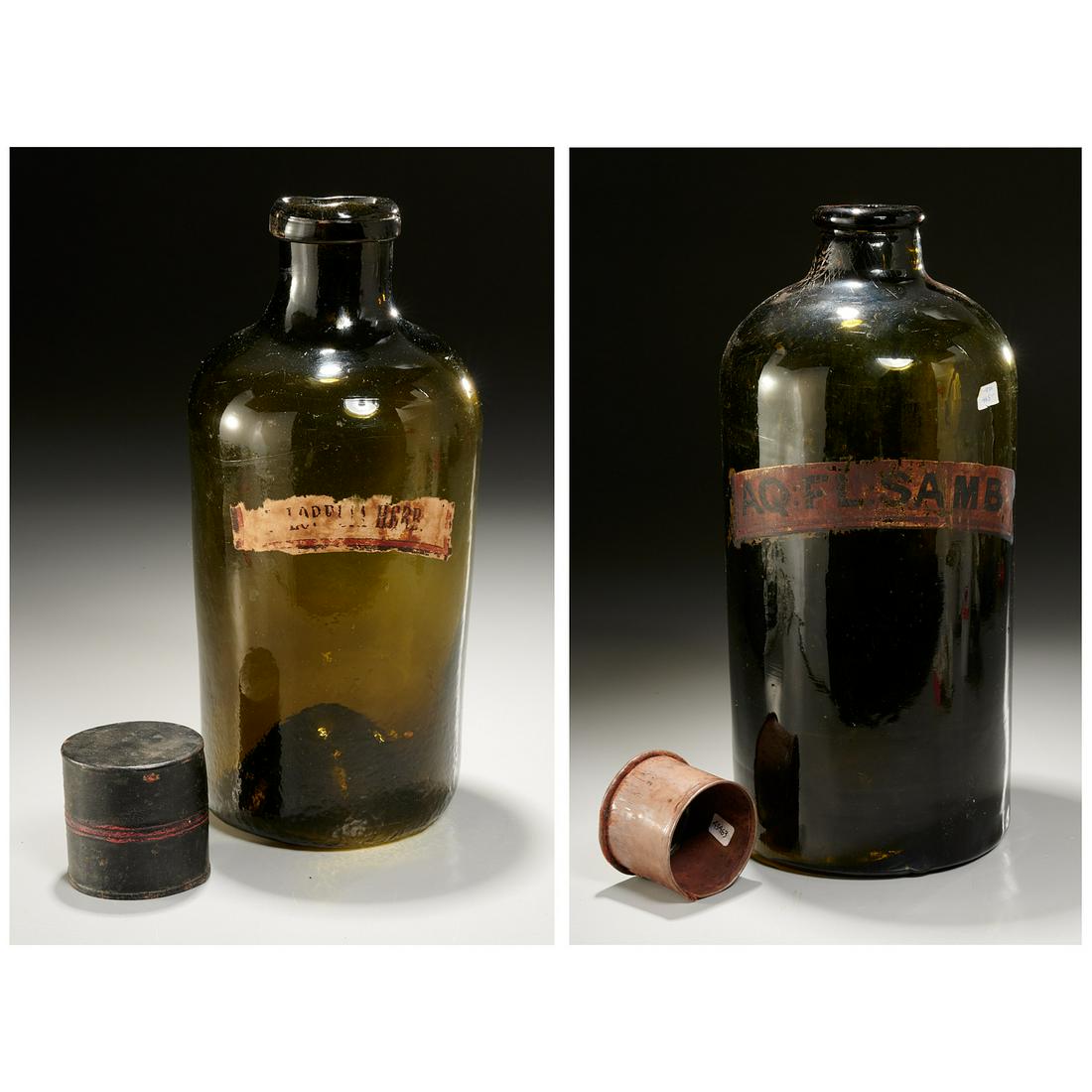 (2) large green glass apothecary jars: (2) large green glass apothecary jars, 19th c., one with smis-shaped top and uneven, dimpled bottom, with painted metal cap, paper label, 10.75"h x 4.25"dia; with green glass jar with very thick botto