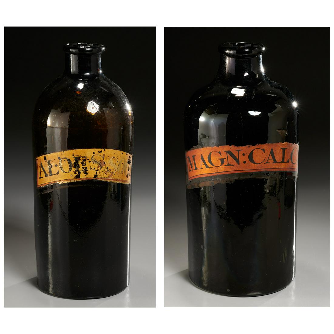 (2) Large amber & green glass apothecary jars: (2) Large amber & green glass apothecary jars, Amber jar labeled "Aloe S. Soc", 13.5"h x 5.25"dia; green jar labeled "Magn: Calc:", remnant of old label on reverse, 14"h x 6.25"dia