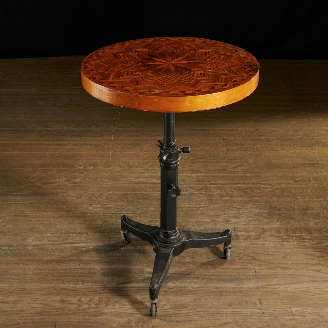 Unusual Continental parquetry and cast iron table: Unusual Continental parquetry and cast iron table, 20th c., thick rotating circular top on adjustable height cast iron tripod pedestal base with casters, 36"h (can adjust taller) x 25"dia
