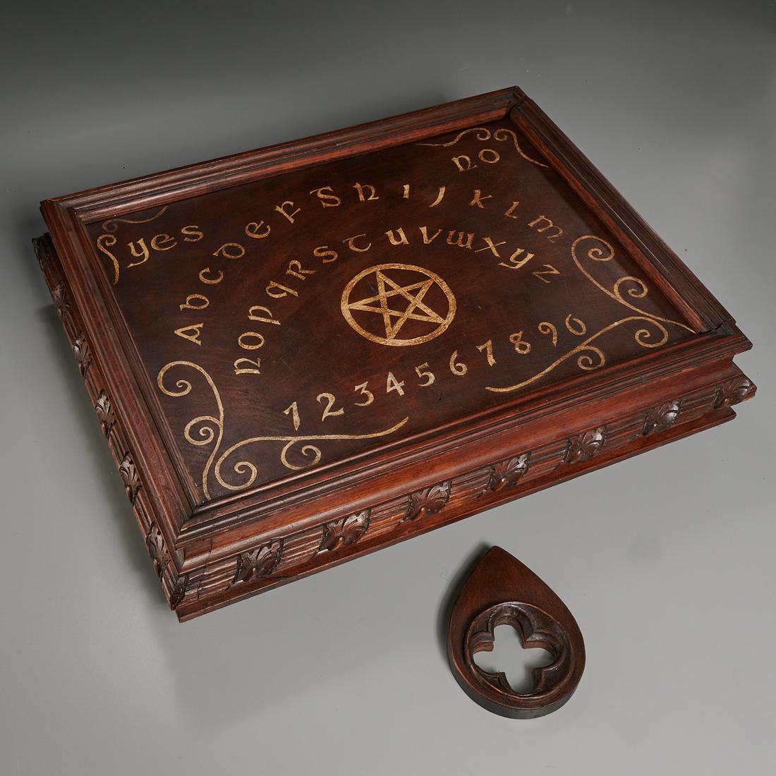 Ornately carved Ouija board in Victorian case: Ornately carved Ouija board in Victorian case, 19th c. and later, solid wood carved box on pedestal legs, carved devil cover reverses to gold-lettered board, side folds down to allow top to slide out,