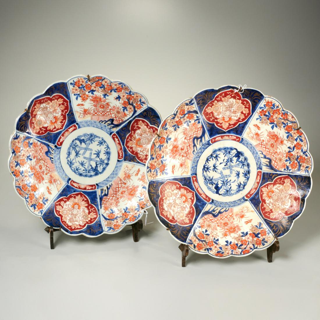 Pair antique Japanese Imari chargers: Pair antique Japanese Imari chargers, Likely 19th c., each with central blue and white bamboo decoration, scalloped edge, floral paneled border, and delicate wooden stand, 14.5"dia (charger), 12"h x 9